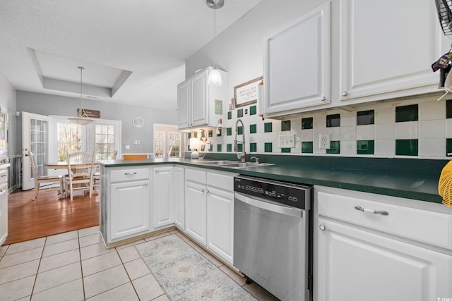 kitchen featuring sink, white cabinetry, stainless steel dishwasher, a tray ceiling, and pendant lighting