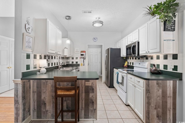 kitchen with stainless steel appliances, kitchen peninsula, sink, and white cabinets