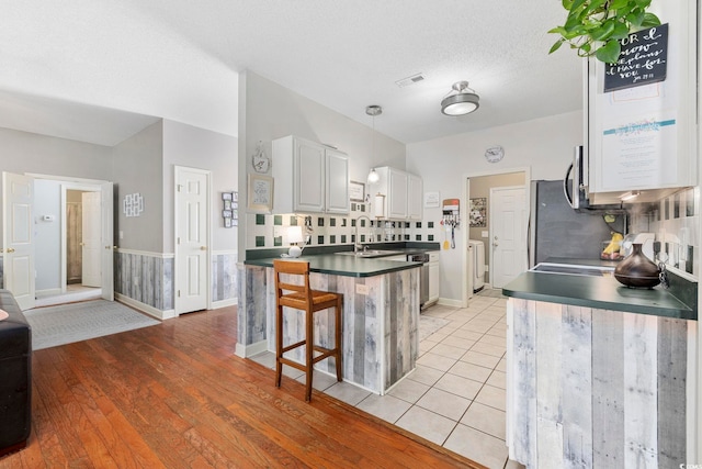 kitchen with pendant lighting, white cabinets, a kitchen breakfast bar, kitchen peninsula, and washing machine and dryer