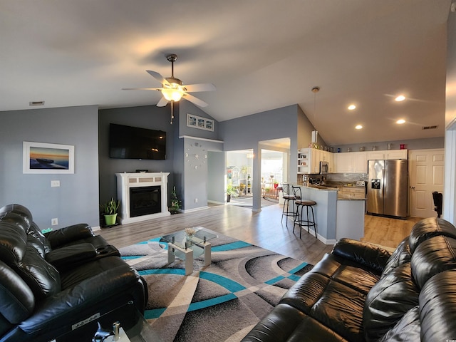 living room with vaulted ceiling, ceiling fan, and light hardwood / wood-style floors