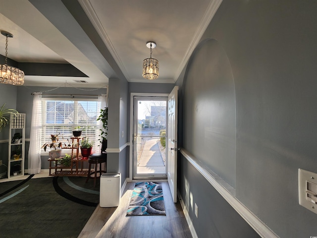 entryway featuring a notable chandelier, hardwood / wood-style flooring, and ornamental molding