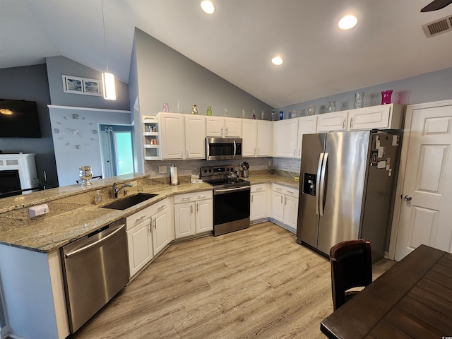 kitchen featuring appliances with stainless steel finishes, decorative light fixtures, white cabinetry, sink, and light stone counters