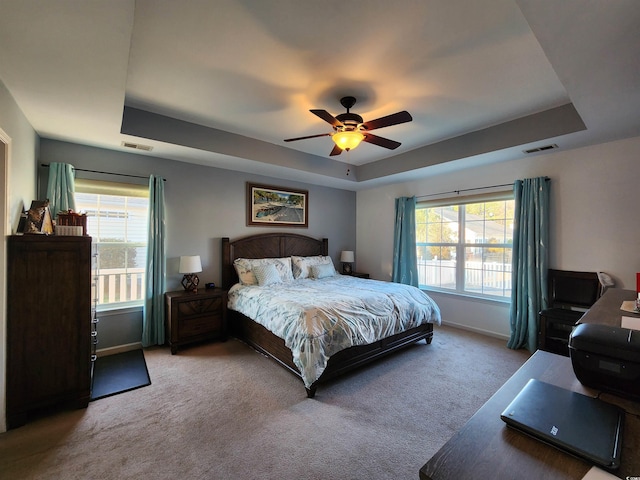 carpeted bedroom featuring ceiling fan and a tray ceiling