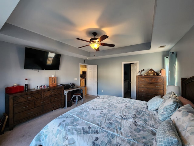 bedroom with light carpet, a tray ceiling, and ceiling fan