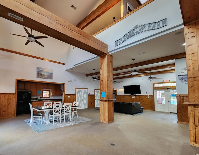 dining area featuring beamed ceiling, light colored carpet, and wooden walls