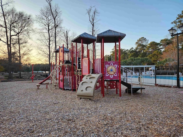 playground at dusk featuring a community pool