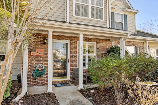 property entrance featuring a porch and brick siding