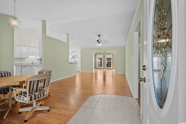 entryway featuring lofted ceiling, light wood-style floors, baseboards, and ceiling fan with notable chandelier