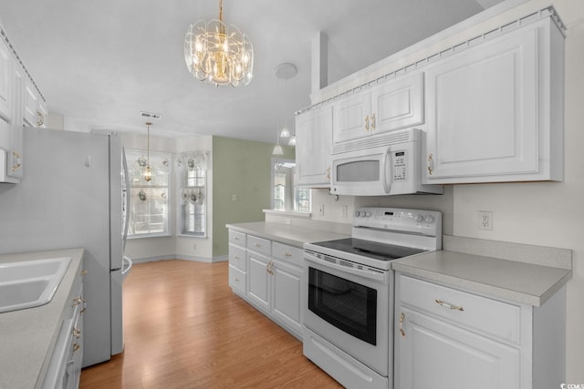 kitchen featuring a chandelier, light countertops, white appliances, and white cabinets