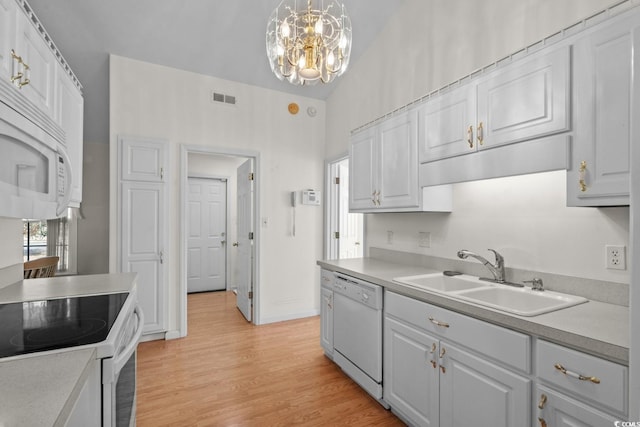 kitchen with light countertops, white appliances, visible vents, and a sink