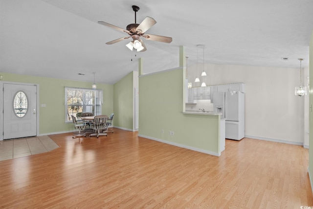 unfurnished living room featuring light wood-type flooring, baseboards, a ceiling fan, and lofted ceiling