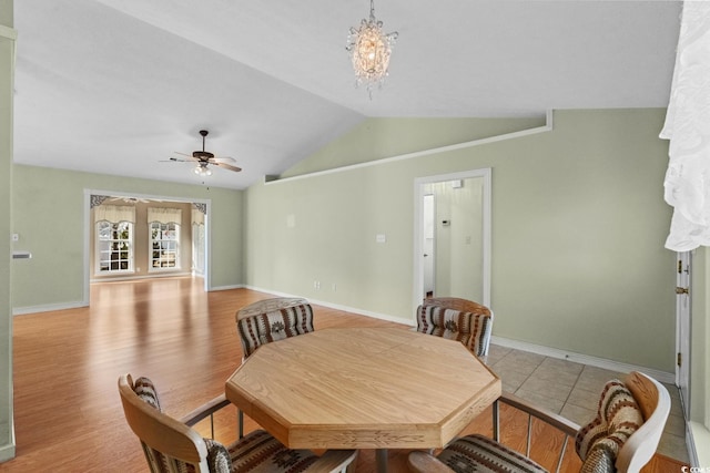 dining space with light wood-style floors, vaulted ceiling, baseboards, and ceiling fan with notable chandelier