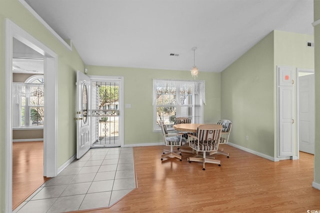 dining room featuring lofted ceiling, baseboards, visible vents, and light wood finished floors