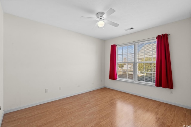 unfurnished room featuring a ceiling fan, wood finished floors, visible vents, and baseboards