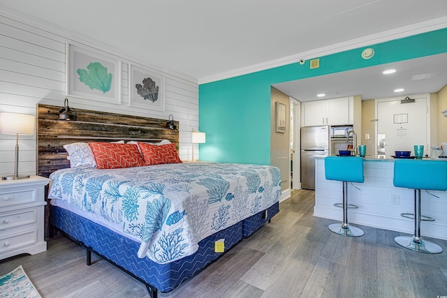 bedroom with sink, crown molding, stainless steel fridge, and wood-type flooring