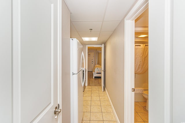 hallway featuring a paneled ceiling and light tile patterned floors