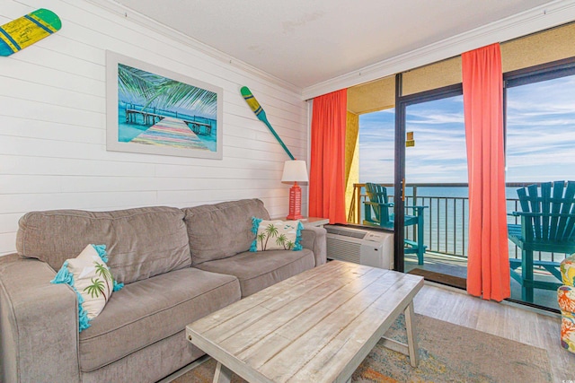 living room featuring wood walls, a water view, crown molding, and wood-type flooring