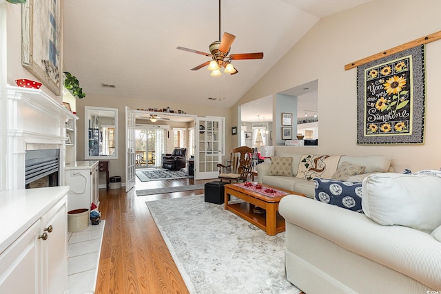 living room featuring ceiling fan, high vaulted ceiling, and light hardwood / wood-style flooring