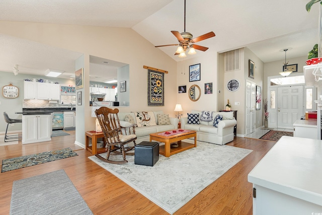 living room featuring high vaulted ceiling, ceiling fan, and light hardwood / wood-style flooring