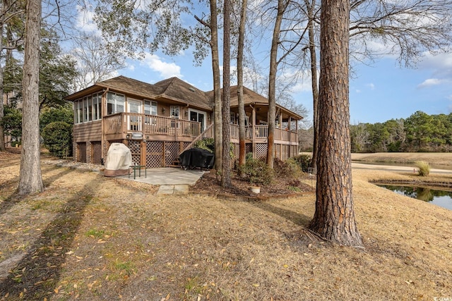 back of house with a wooden deck, a patio, and a sunroom