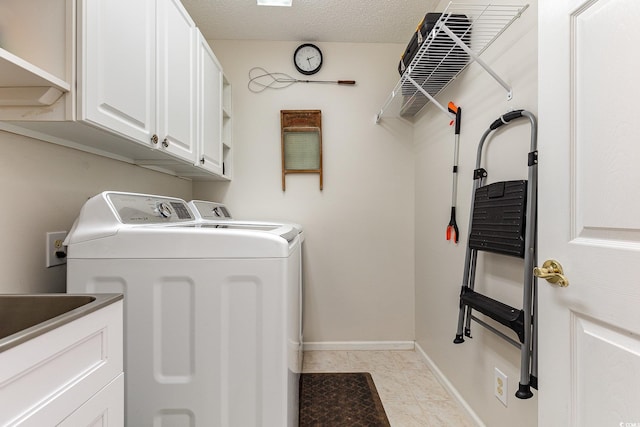 laundry area with washer and dryer, light tile patterned floors, cabinets, and a textured ceiling