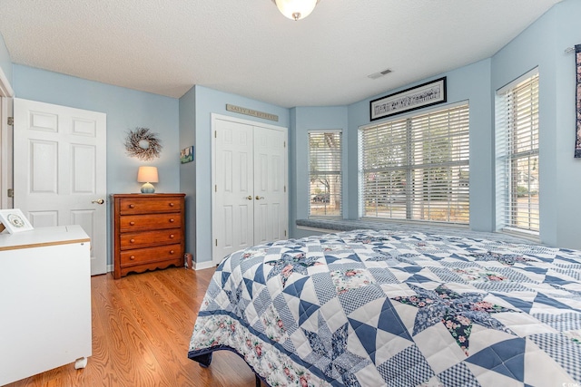 bedroom with light hardwood / wood-style floors, a closet, and a textured ceiling