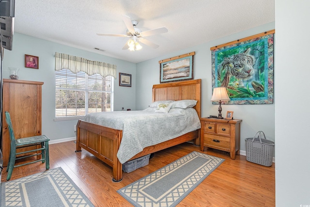 bedroom with wood-type flooring, ceiling fan, and a textured ceiling