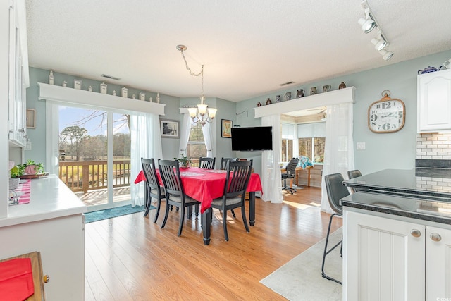 dining room featuring an inviting chandelier, a textured ceiling, and light wood-type flooring