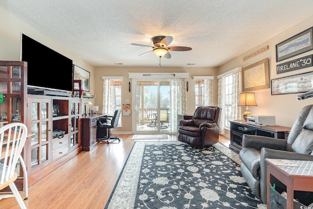 living room featuring a textured ceiling, light hardwood / wood-style flooring, and ceiling fan