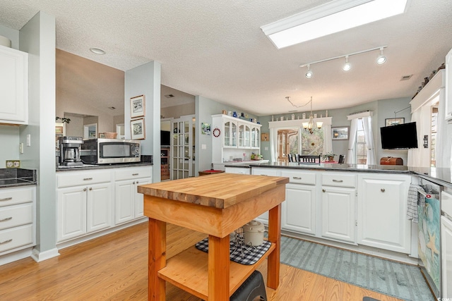 kitchen with white cabinetry, kitchen peninsula, an inviting chandelier, and light wood-type flooring