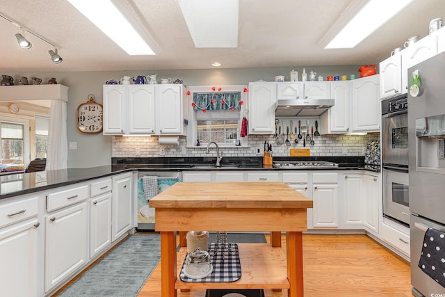 kitchen with sink, light hardwood / wood-style flooring, white cabinets, and appliances with stainless steel finishes