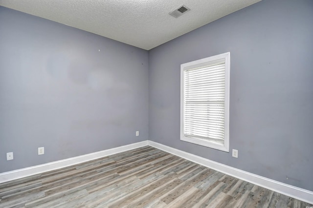 unfurnished room featuring a textured ceiling and light hardwood / wood-style flooring