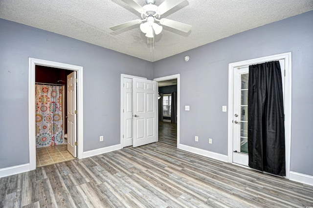 unfurnished bedroom with ensuite bathroom, ceiling fan, a textured ceiling, and light hardwood / wood-style floors