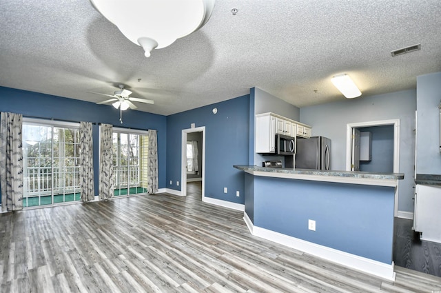 kitchen with light hardwood / wood-style flooring, appliances with stainless steel finishes, kitchen peninsula, ceiling fan, and white cabinets