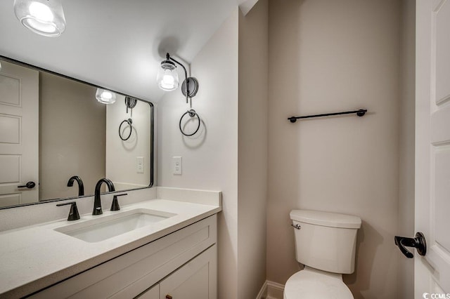 bathroom featuring baseboards, vanity, and toilet