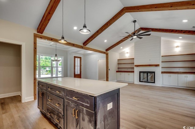 kitchen with decorative light fixtures, light wood-type flooring, baseboards, lofted ceiling with beams, and a fireplace