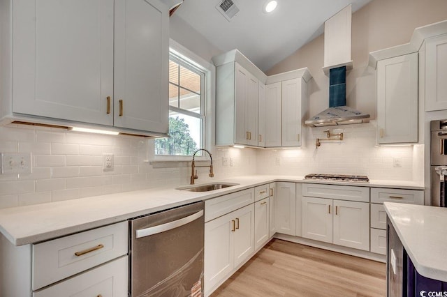 kitchen featuring a sink, light countertops, wall chimney exhaust hood, appliances with stainless steel finishes, and visible vents