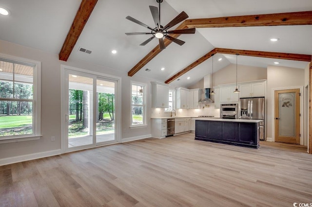 kitchen with stainless steel appliances, light countertops, visible vents, wall chimney range hood, and beamed ceiling