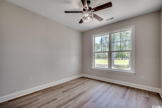empty room featuring baseboards, wood finished floors, and visible vents
