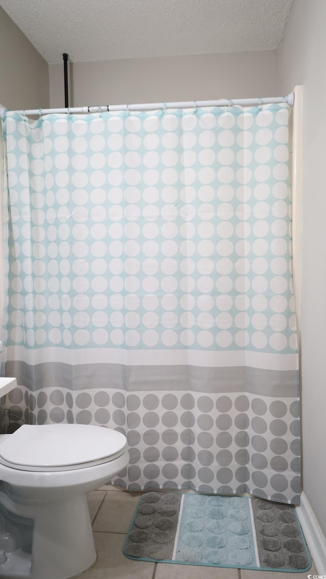 bathroom with tile patterned flooring, toilet, and a textured ceiling