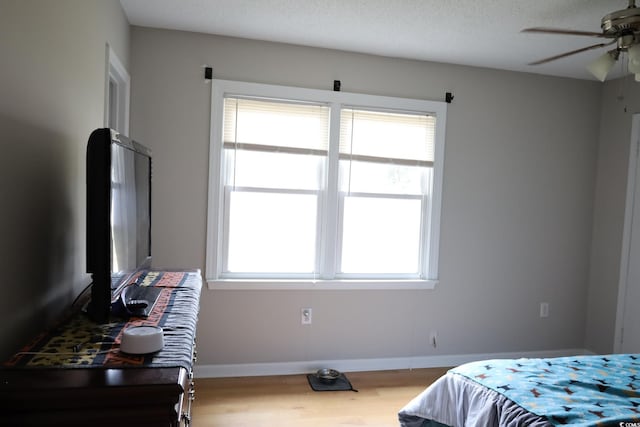 bedroom featuring ceiling fan, hardwood / wood-style floors, and a textured ceiling