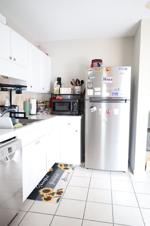 kitchen with light tile patterned flooring, appliances with stainless steel finishes, sink, and white cabinets