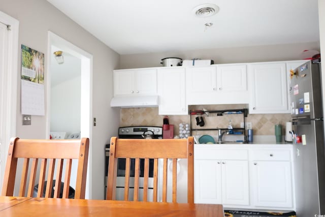 kitchen with sink, stainless steel fridge, stove, white cabinetry, and tasteful backsplash