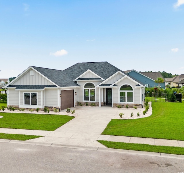 modern inspired farmhouse with a shingled roof, concrete driveway, an attached garage, board and batten siding, and a front yard