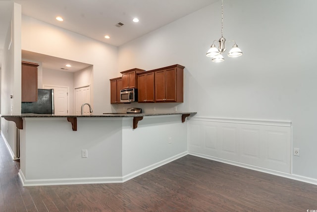 156 Parmelee Dr Unit B, Murrells Inlet, SC 29576 - kitchen with stainless steel microwave, freestanding refrigerator, a breakfast bar area, dark stone countertops, and dark wood-style flooring