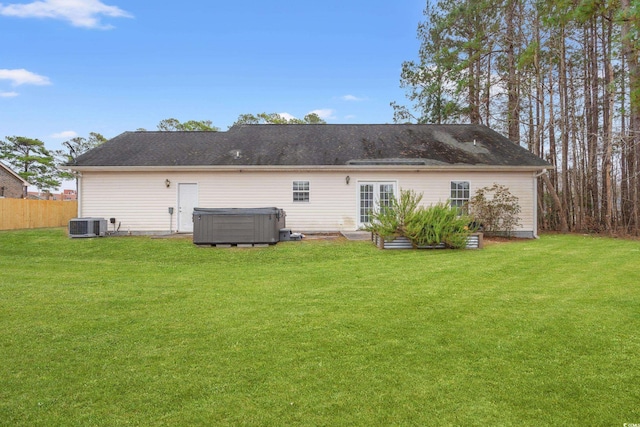 back of property with a hot tub, a lawn, and central air condition unit