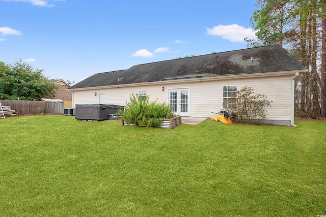 back of property featuring a lawn, a hot tub, french doors, and central air condition unit