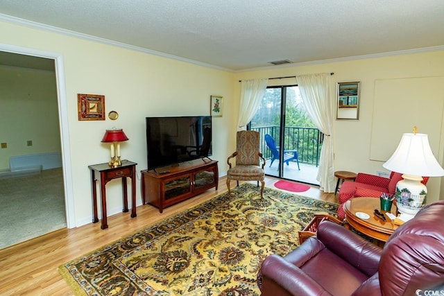 living area with a textured ceiling, wood finished floors, baseboards, and ornamental molding