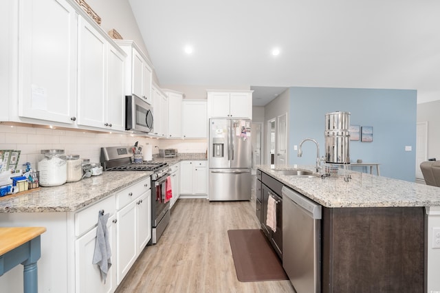 kitchen with stainless steel appliances, light stone countertops, sink, and white cabinets