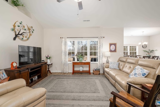 living room featuring hardwood / wood-style flooring, vaulted ceiling, and ceiling fan with notable chandelier